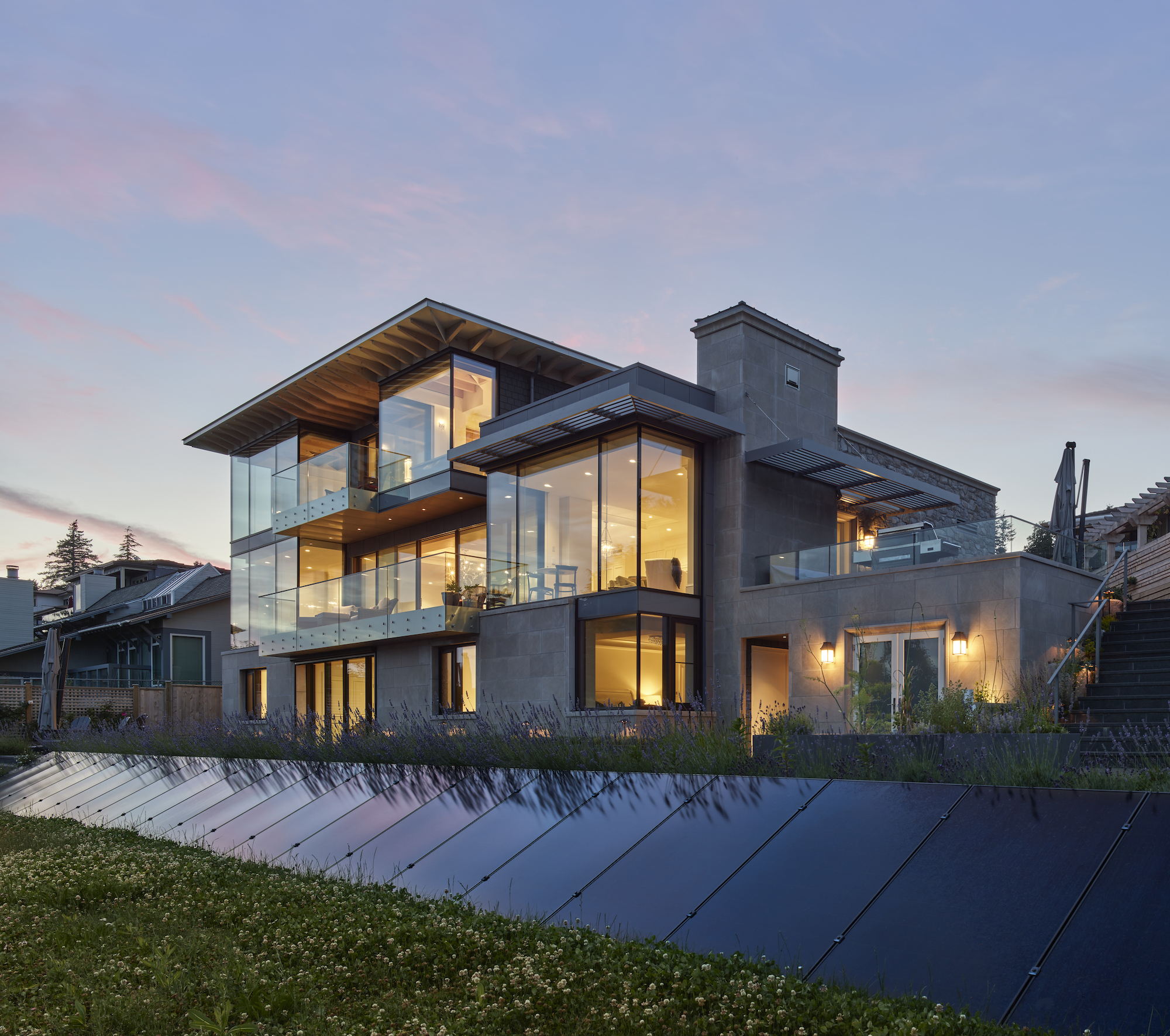 Solar panels line the front yard of a modern home
