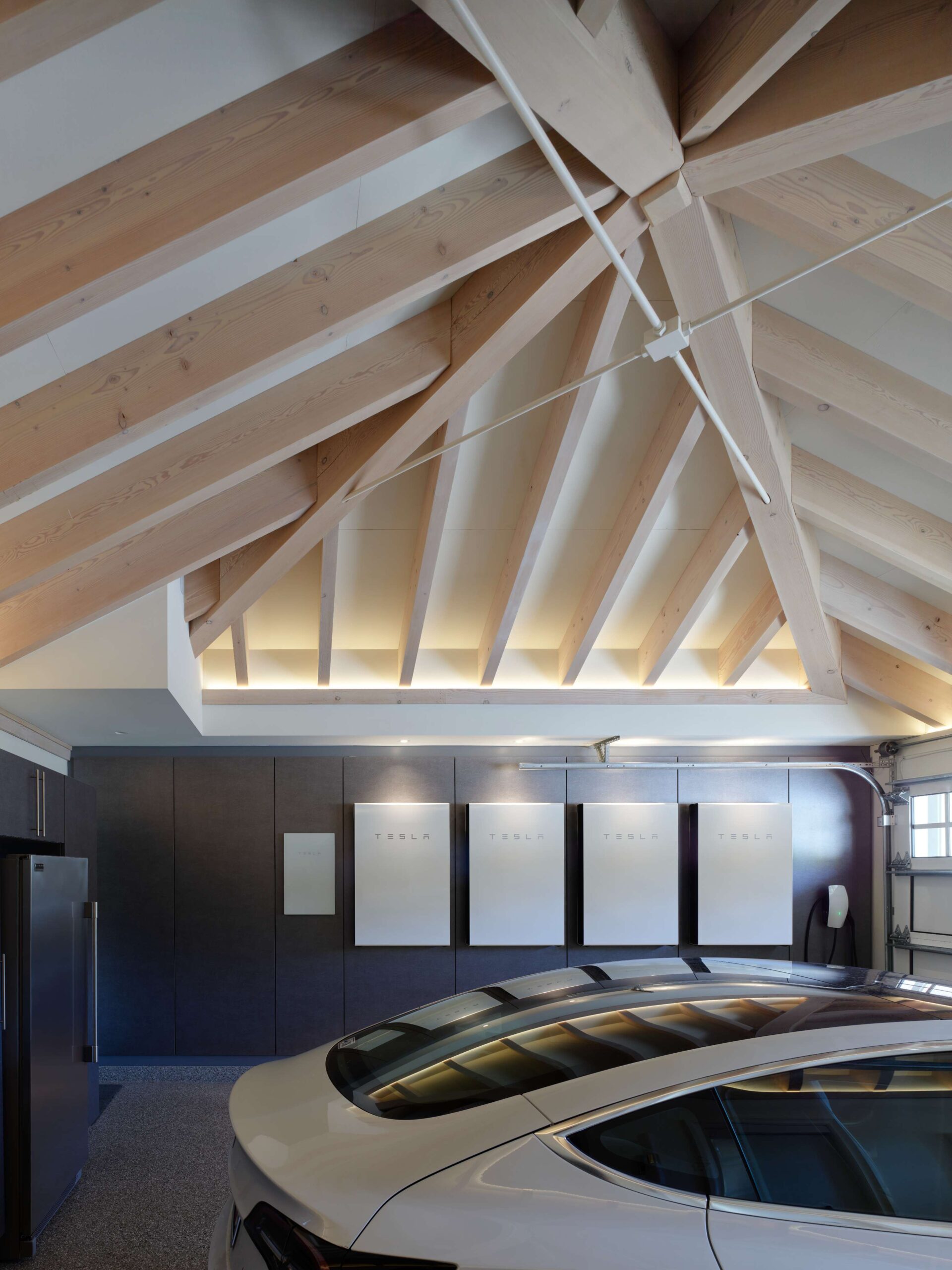 A grid of Tesla Powerwalls line the interior of a car garage