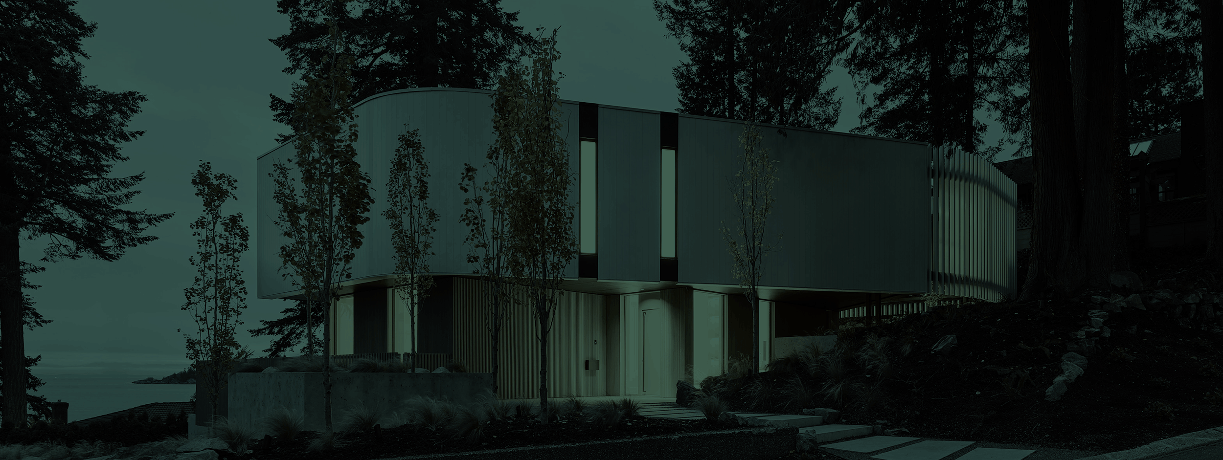 A unique custom home is surrounded by trees in its waterfront location. The image is tinted dark green.