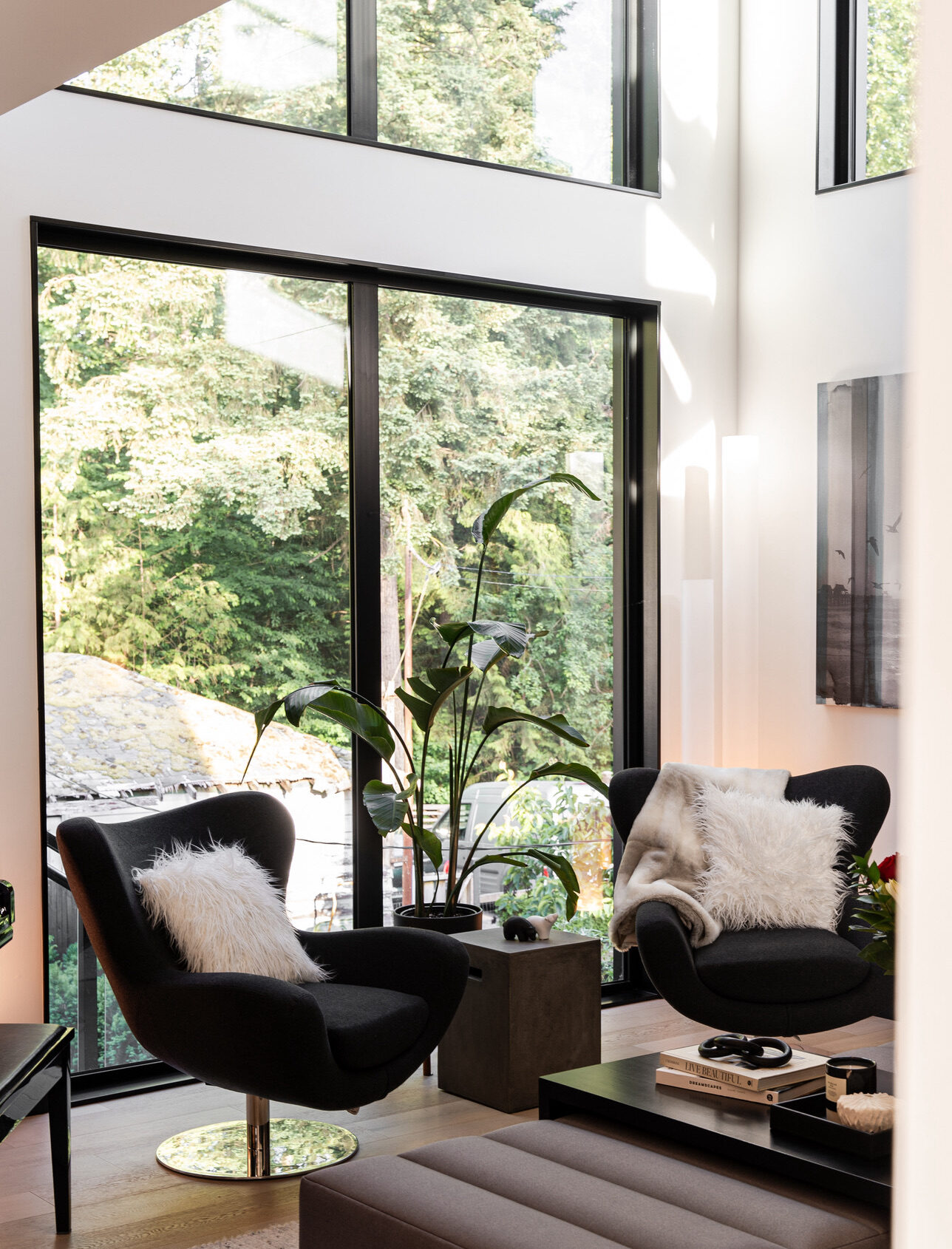 The view into the living room of a custom built home with armchairs and big windows.