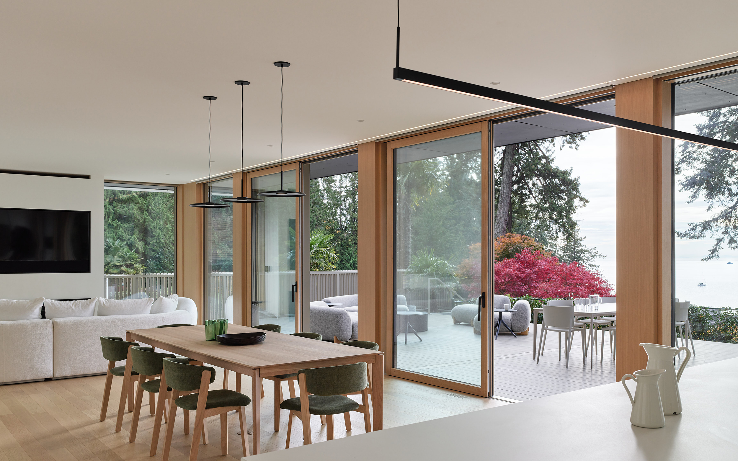 Modern dining area with large sliding glass doors opening to outdoor terrace and ocean view