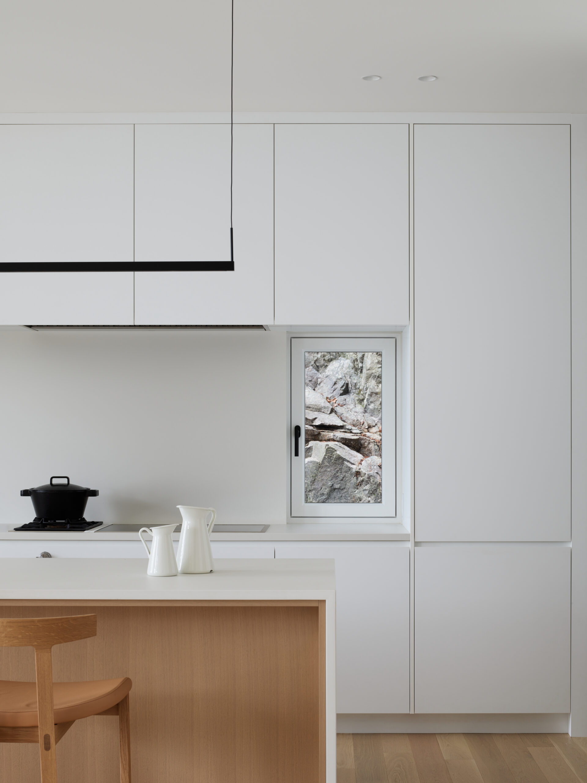 Contemporary kitchen with white cabinets, integrated appliances, and minimalist lighting design